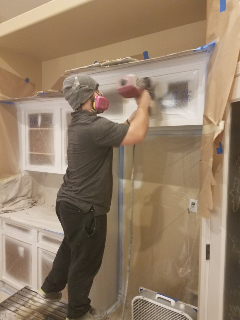 worker refinishing cabinets