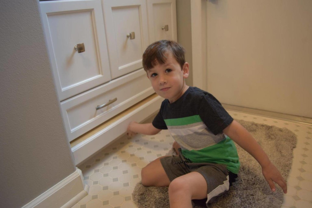 young boy putting custom built cabinet pull out stool away