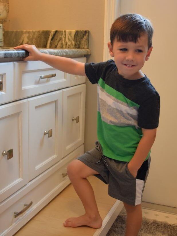 young boy standing on custom built cabinet pull out stool