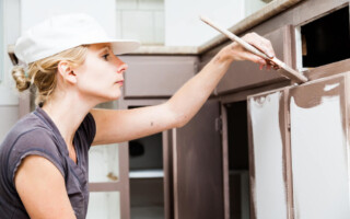 closeup of a woman painting cabinets
