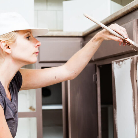 closeup of a woman painting cabinets