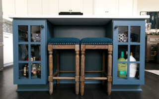 Kitchen island with built in blue cabinets and stools in between