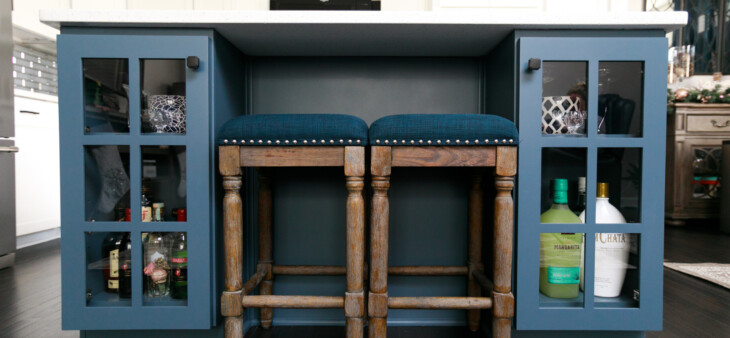 Kitchen island with built in blue cabinets on either side and two stools between
