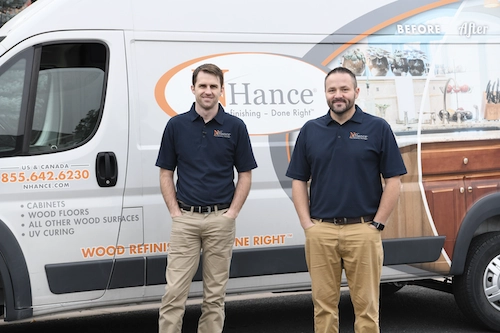 Two N-Hance employees, dressed in khaki pants and dark blue polos, stand in front of an N-Hance van.